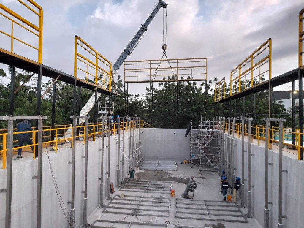 Izaje y montaje de estructura metálica industrial con grúa telescópica y pasamanos amarillos de seguridad por TUBERSOLD SAS